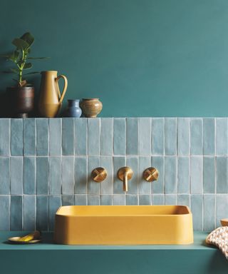 A blue bathroom with a light blue glossy Zellige tile upstanding and a yellow sink