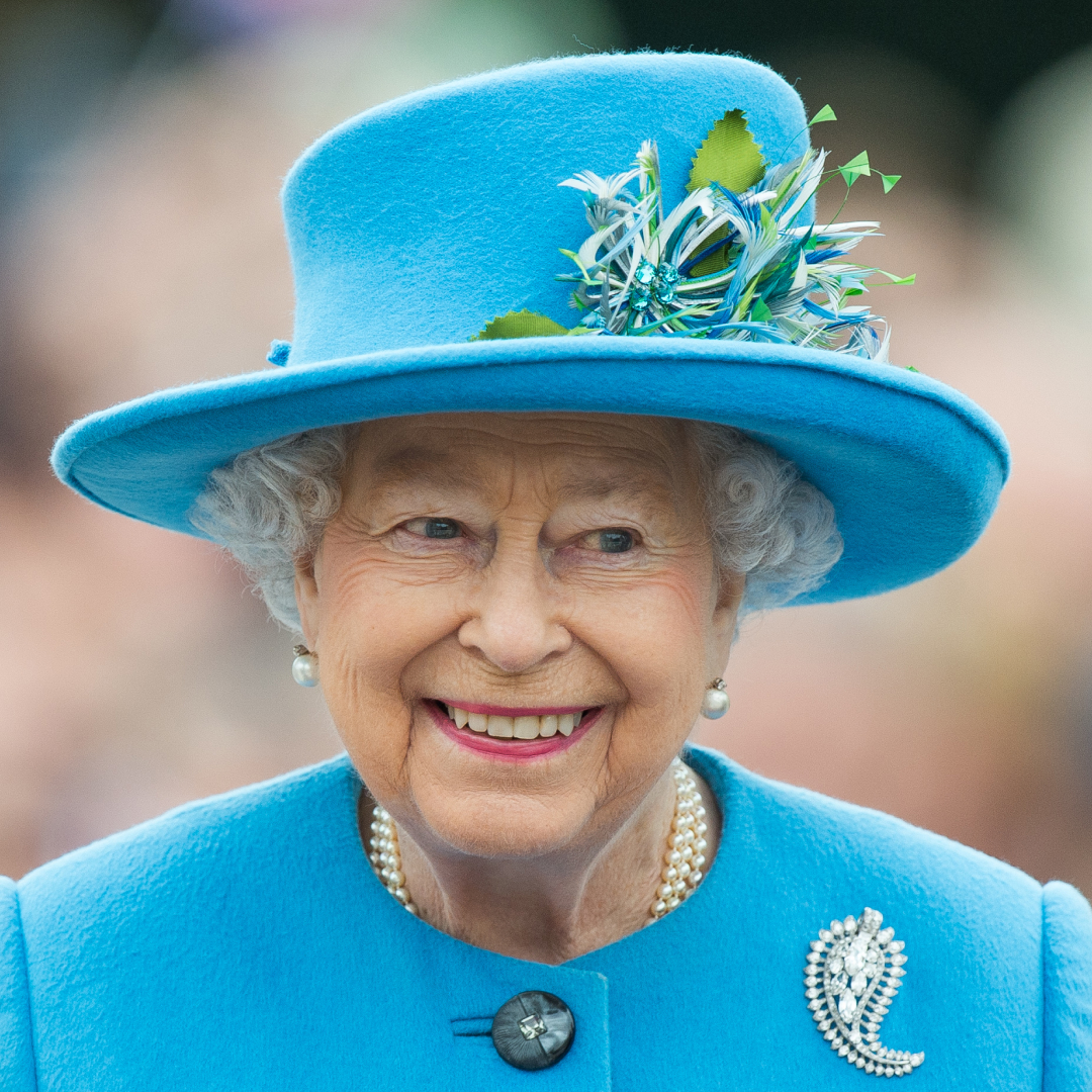 Queen Elizabeth wearing a turquoise hat and coat and smiling