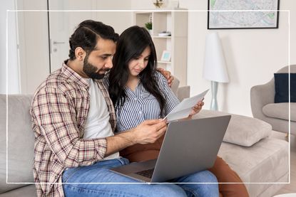 couple sitting on sofa with laptop, looking at energy bills