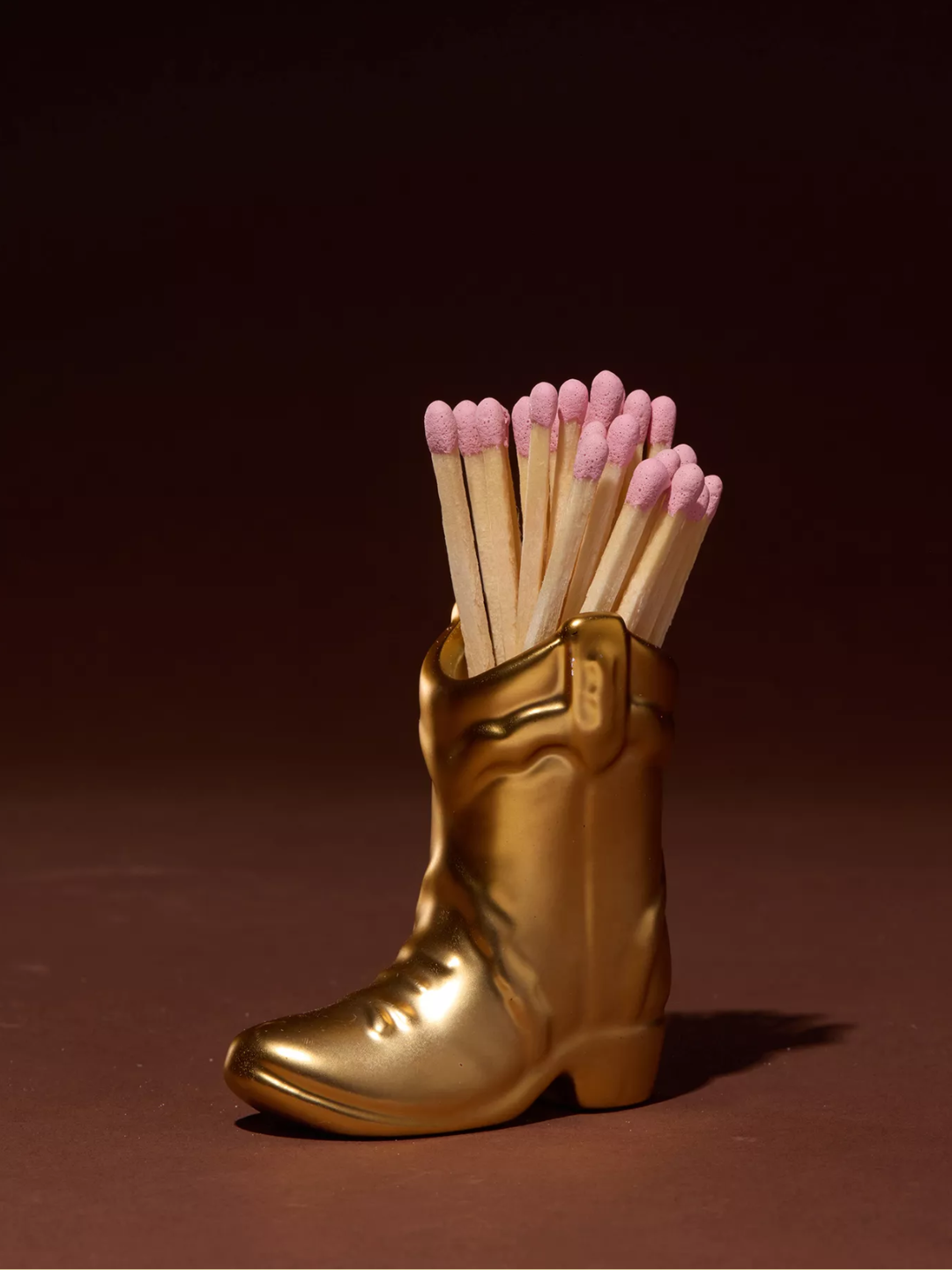 A gold cowboy boot match holder from Paddywax