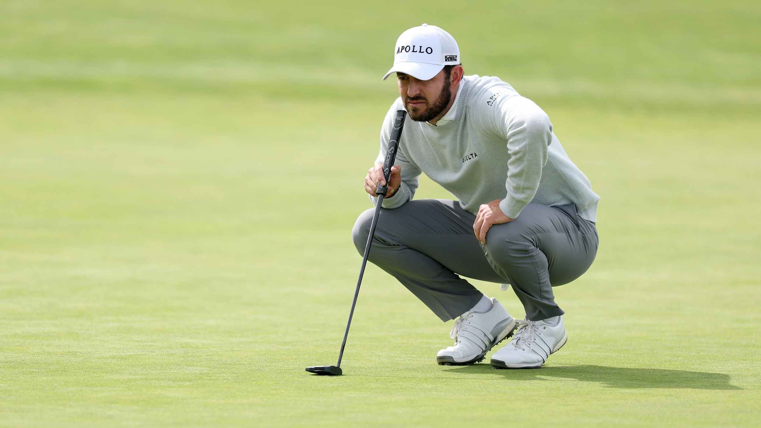 Patrick Cantlay crouching down reading a putt at the 2026 US Open