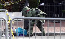 A member of the bomb squad investigates a suspicious item on the road near Kenmare Square on April 15.