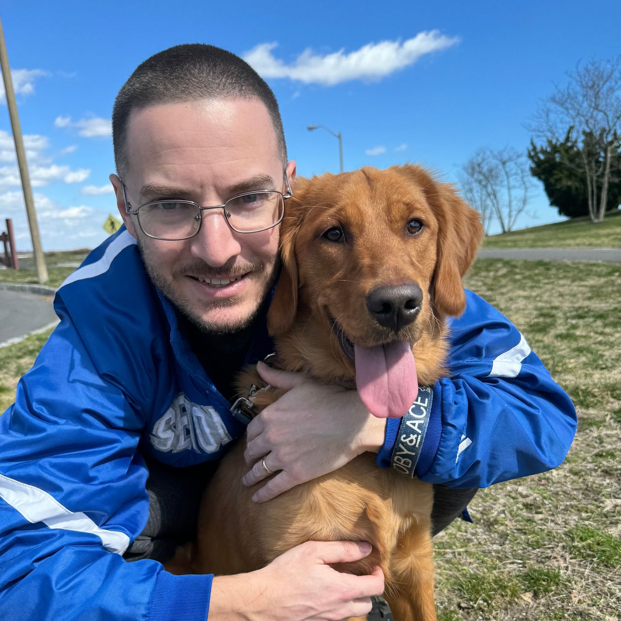 Brent hugging his dog Sandy outside on the grass