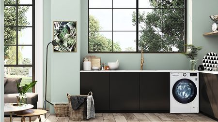 A kitchen with green wall paint decor and washing machine under kitchen sink