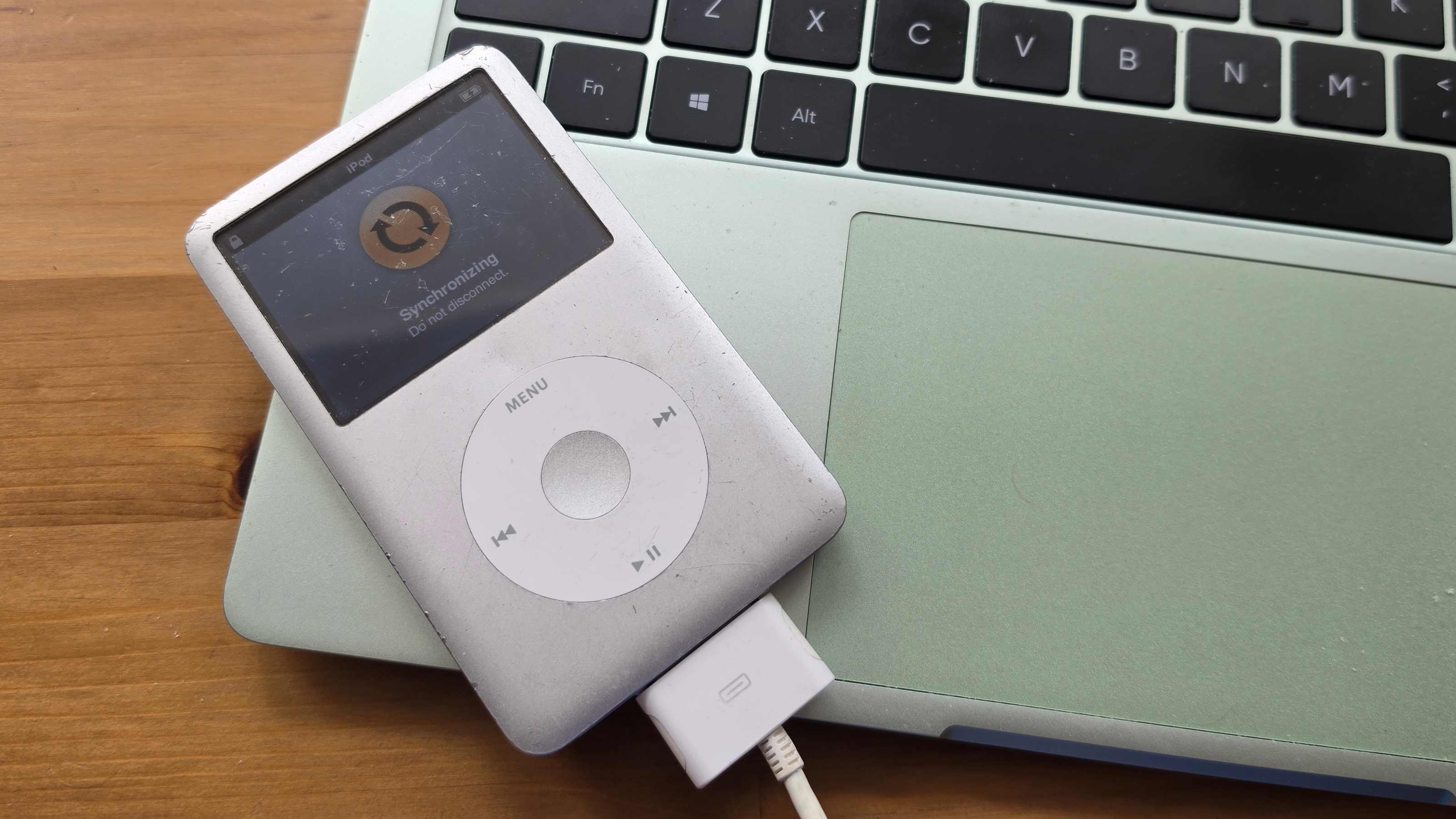 The iPod Classic connected to a green Realme laptop, showing iTunes.