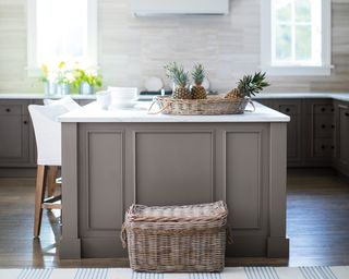 A small grey kitchen island in a bright kitchen