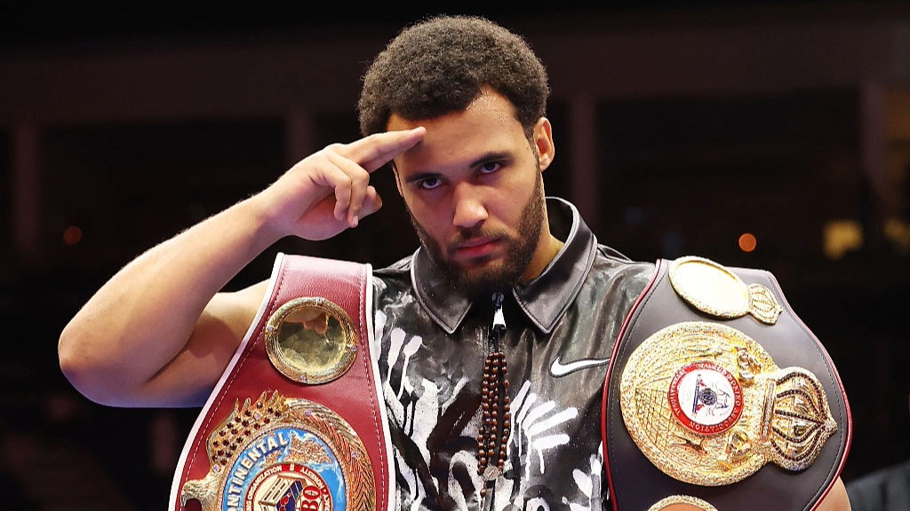 Moses Itauma salutes the crowd, wearing two minor heavyweight boxing belts.