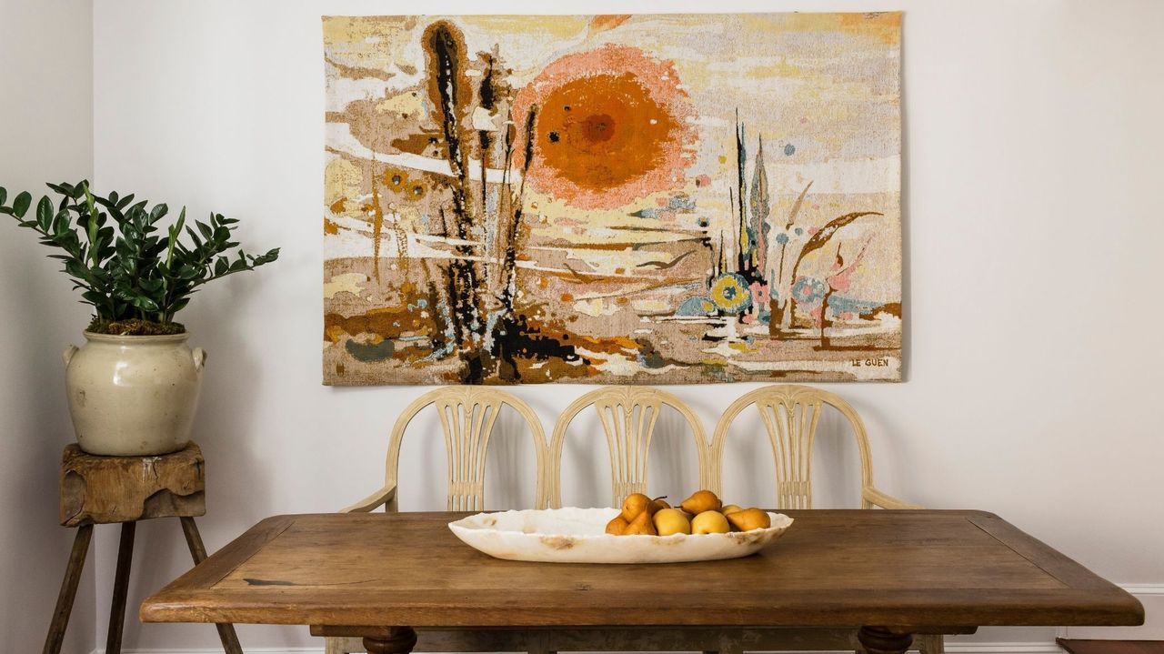 wood dining table with fruit arrangement, art and plant pot on stool