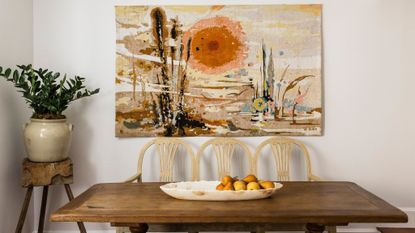 wood dining table with fruit arrangement, art and plant pot on stool