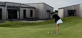Female golfer putts on a putting green