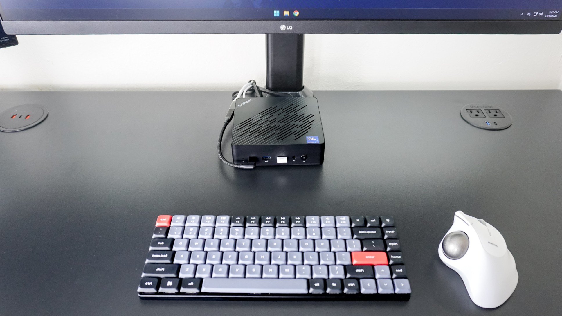 The Minix Elite EU715-AI mini PC on a desk with a mechanical keyboard and trackball mouse
