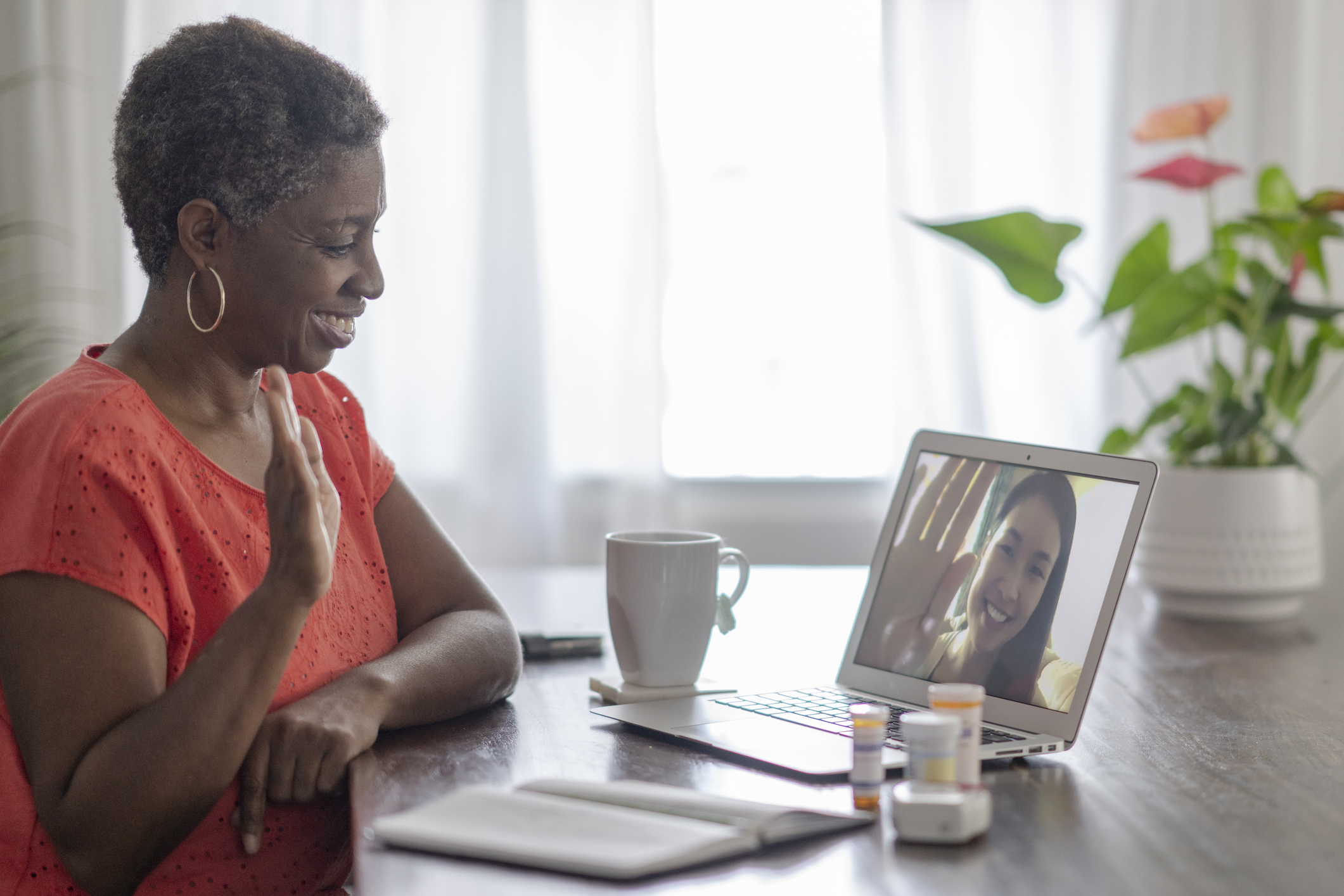 Senior woman sitting in her home speaking with a medical professional via video call due to the COVID-19 lockdown.