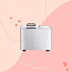 A stainless steel silver bread maker superimposed on a pink background 