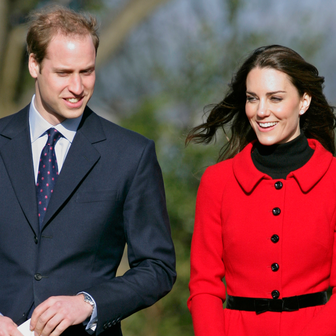 Prince William wears a suit and Kate Middleton wears a bright red coat with black buttons and a black polo neck underneath