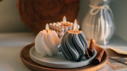 Three sculpted candles with swirl pattern exteriors lit on a tray