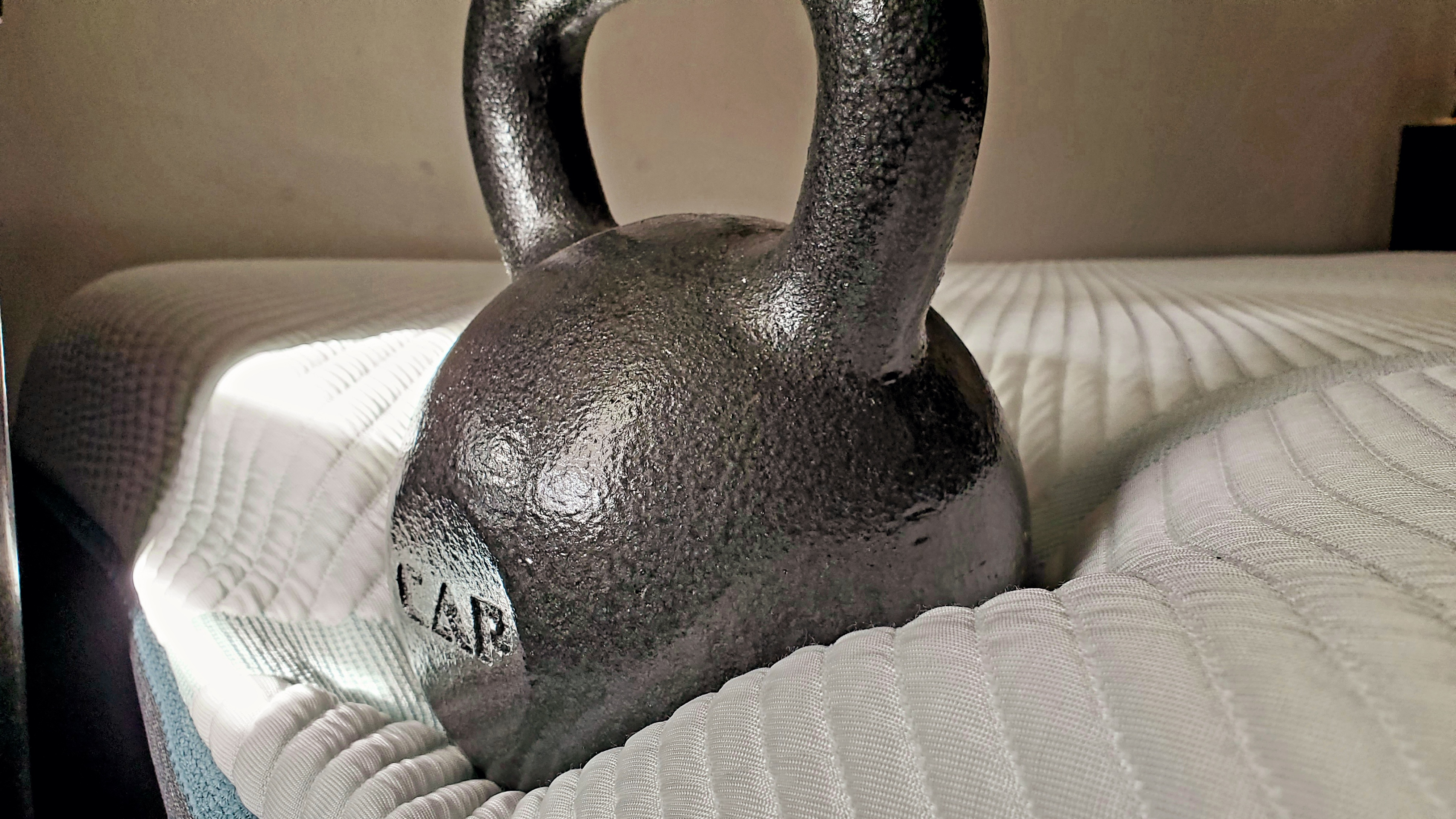 Testing the edge support for the Tempur-Adapt mattress review using a kettlebell.