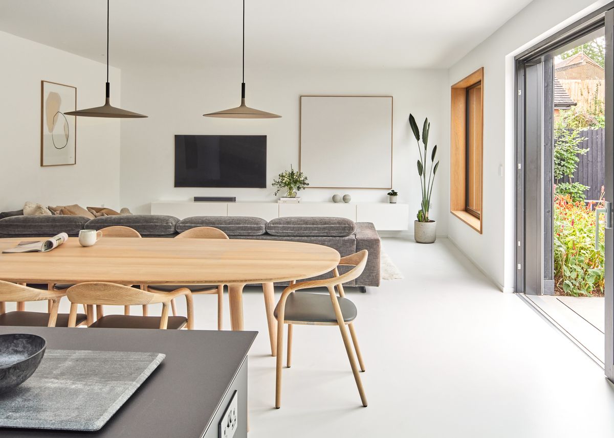 A modern minimalist dining room with glass doors leading out to a patio