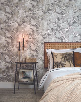 A marble patterned greyscale wallpapered bedroom feature wall