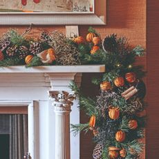 A fireplace decorated with a Christmas garland with dried oranges and pinecones