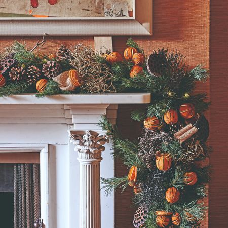 A fireplace decorated with a Christmas garland with dried oranges and pinecones