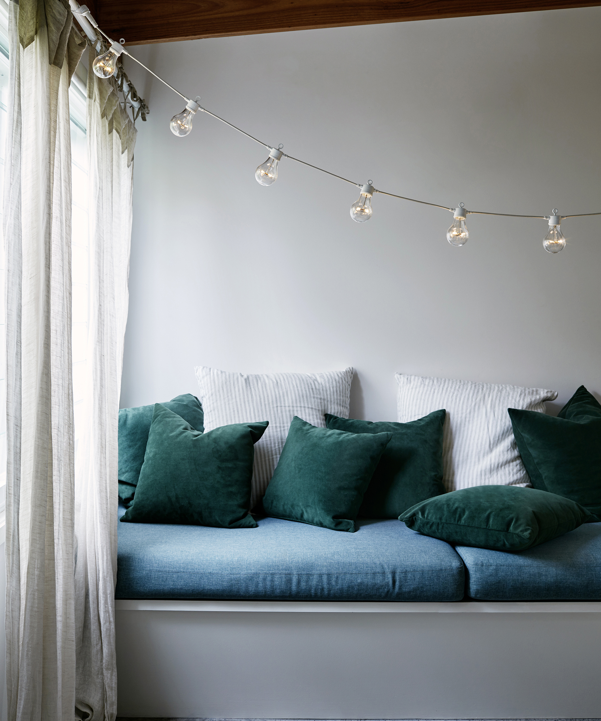 Warm white festoon lights in bedroom with window seating