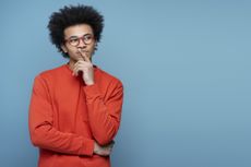 Man in orange shirt thinking about choices.