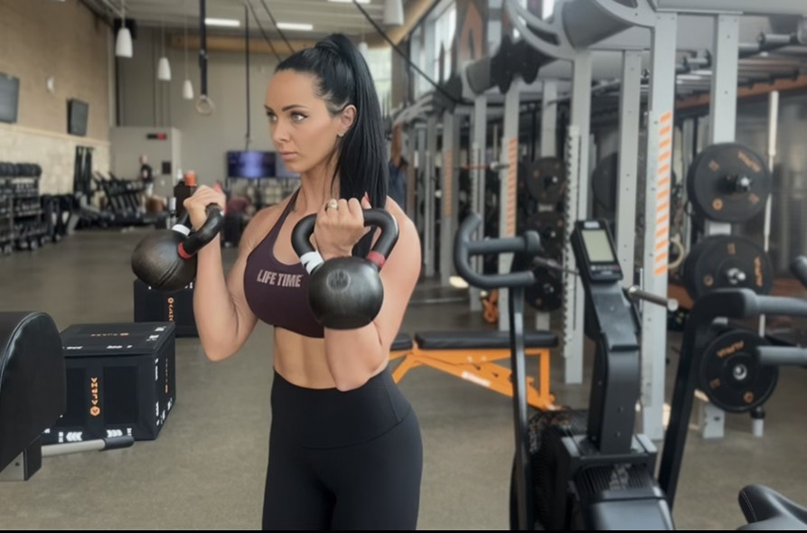 Woman exercises with kettlebells in gym