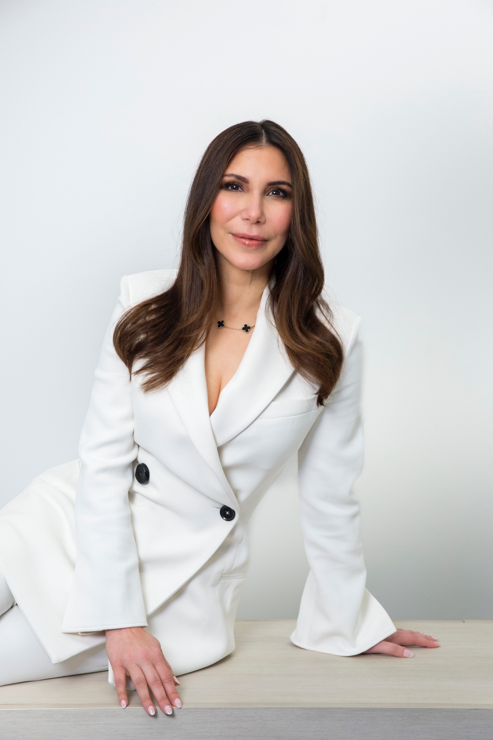 a white woman in a white suit with long brown hair