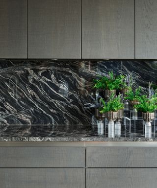 An example of marble kitchen backsplash ideas showing a modern kitchen with a black marble counter and backsplash