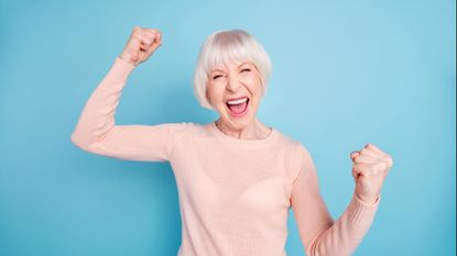 A happy woman pumps her fist in the air.