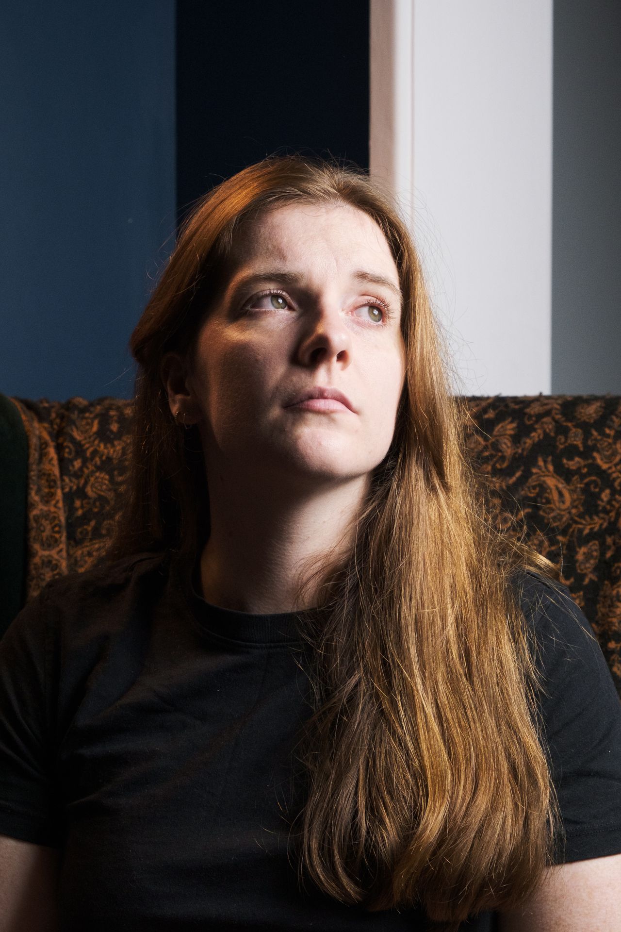 A photograph of a woman sat in a chair looking into the light.