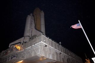 An image of the space shuttle Discovery next to the American flag at the Kennedy Space Center.