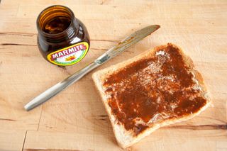 A slice of toast with Marmite on next to an open jar of Marmite