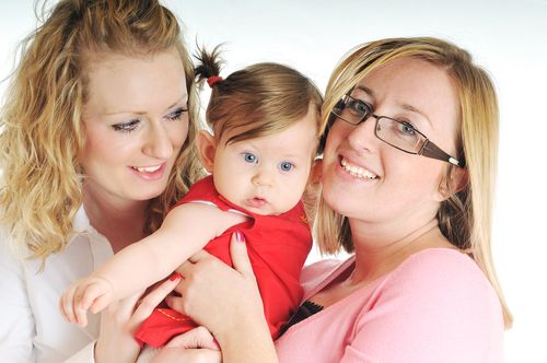 Two women hold a baby between them