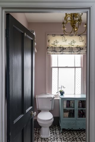 pink bathroom with patterned floor tiles and black door, print window blind