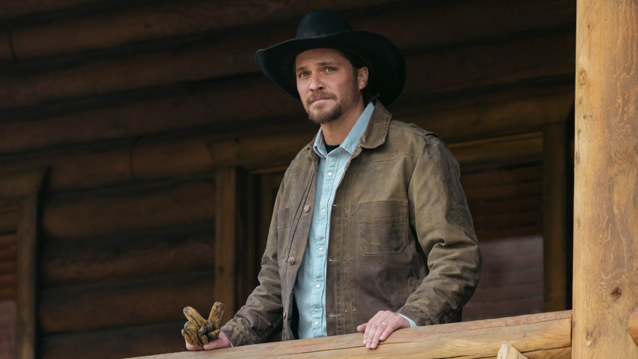 Luke Grimes as Kayce, standing on his porch and holding a pair of work gloves in Marshals.