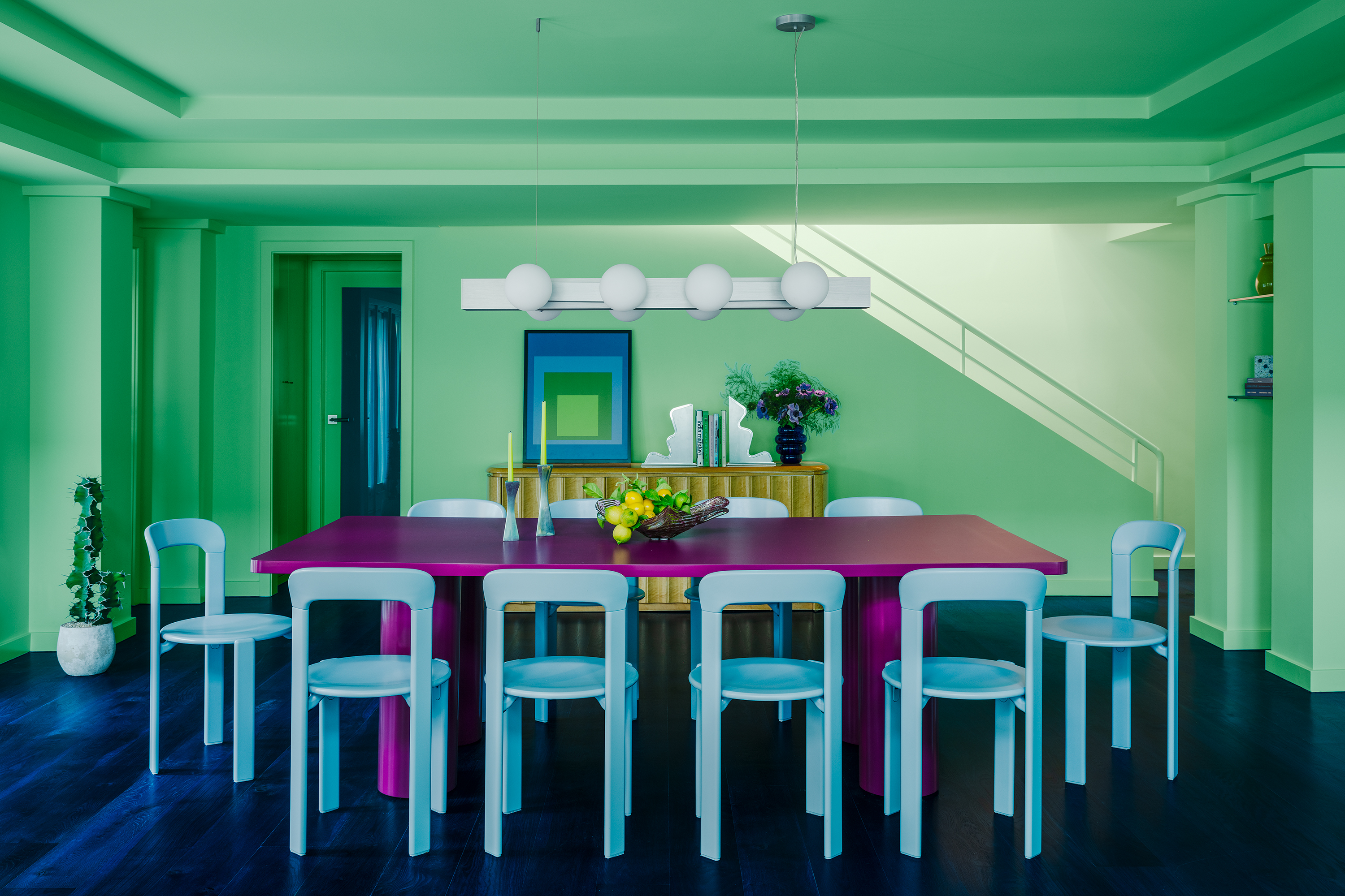 A contemporary dining room in pastel green and blue with a bright purple dining table