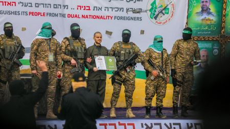 Armed Hamas militants parade Israeli hostages Omer Shem Tov (L) and Omer Wankert on stage in the central Gaza Strip