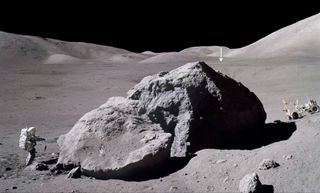 Apollo 17's surface time, the program's longest stay time on the Moon was three days, two hours, fifty-nine minutes. Photo shows Apollo 17's Jack Schmitt carrying a gnomon back towards the lunar rover after observing and sampling the east side of a huge boulder. The vertical arrow in the distance points to the Lunar Module Challenger, located roughly 2 miles (3.1 kilometers) away.