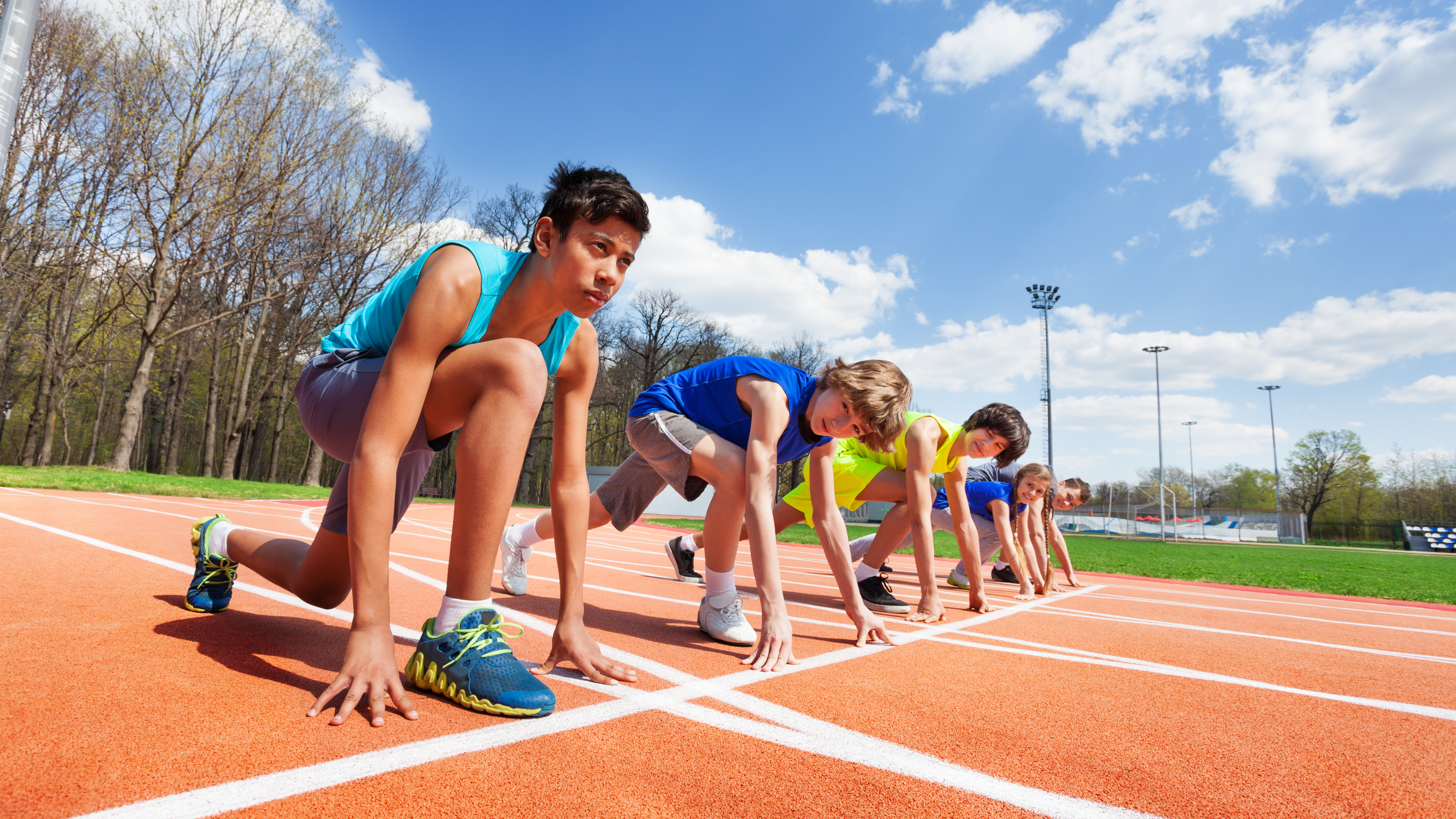 kids lines up on the start line of a running track