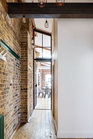 Hallway with exposed brick wall and metal framed windows and door