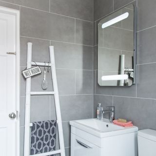 bathroom with grey tiles on wall and ladder