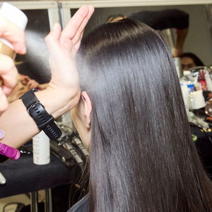model backstage having hair done by a stylist