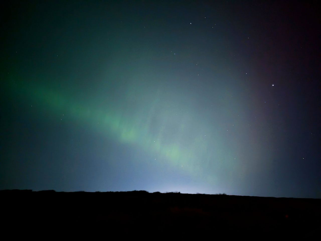 The Northern Lights' green pillars in the night sky