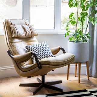 Retro brown leather reclining chair next to a window with a houseplant on a stand