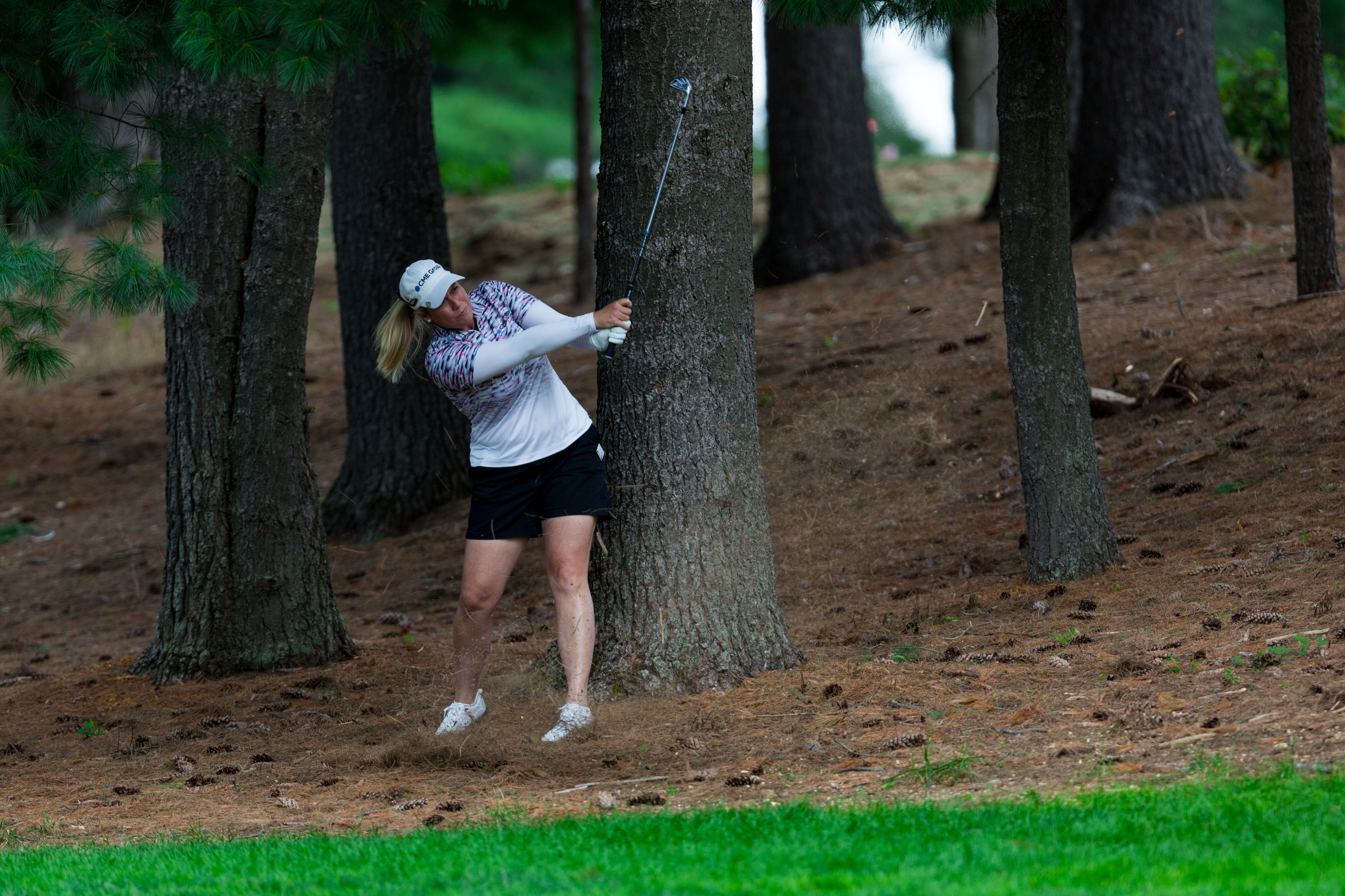 A female golfer hits a shot out of trees
