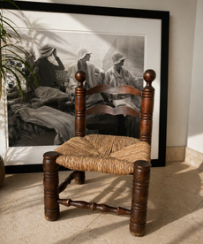 vintage wood chair with rattan base in front of a black and white art print