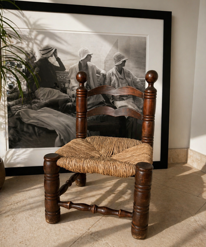 vintage wood chair with rattan base in front of a black and white art print
