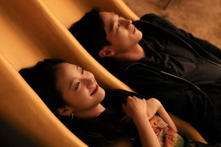 Two people (Kim Go-eun as Jae-hee and Noh Sang-hyun as Heung-soo) lay down on a yellow playground slide, in “Love in the Big City.”