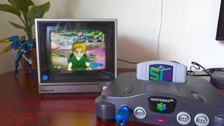 Nintendo 64 console with SummerCart64 inserted on desk with Panasonic CRT TV and Zelda: Nightmare ROM hack on screen.